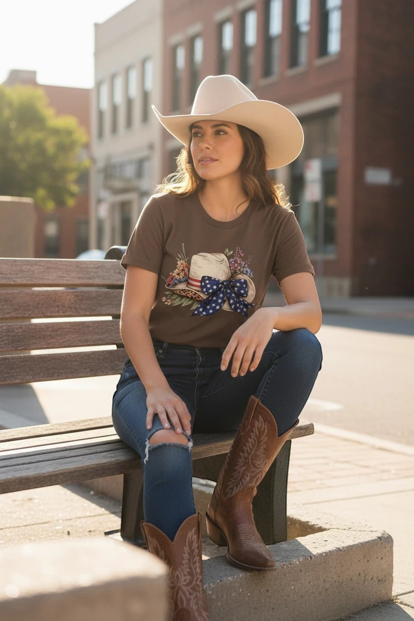 Southern Charm Design Works brown cotton t-shirt with patriotic floral cowboy hat graphic. Model wears jeans and boots.